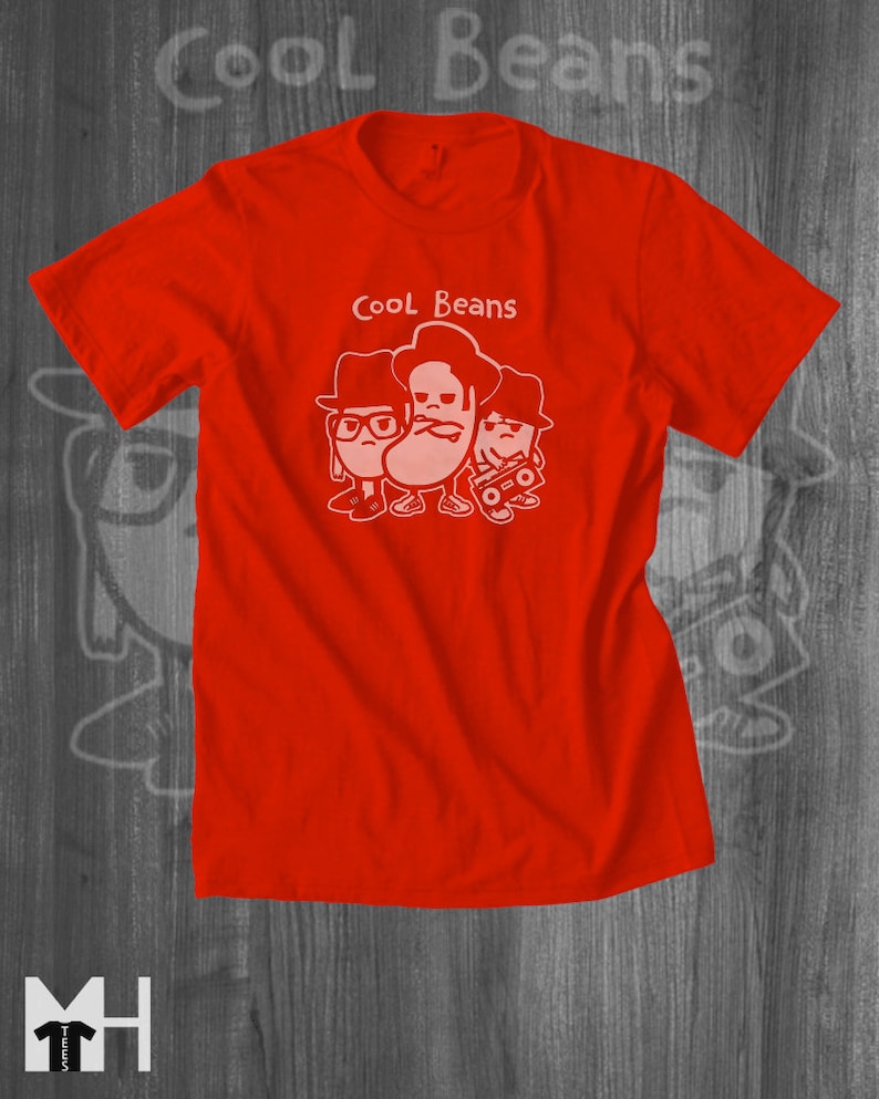 May include: Red t-shirt with a white graphic of three cartoon beans wearing hats and sunglasses. The text "Cool Beans" is printed above the beans.