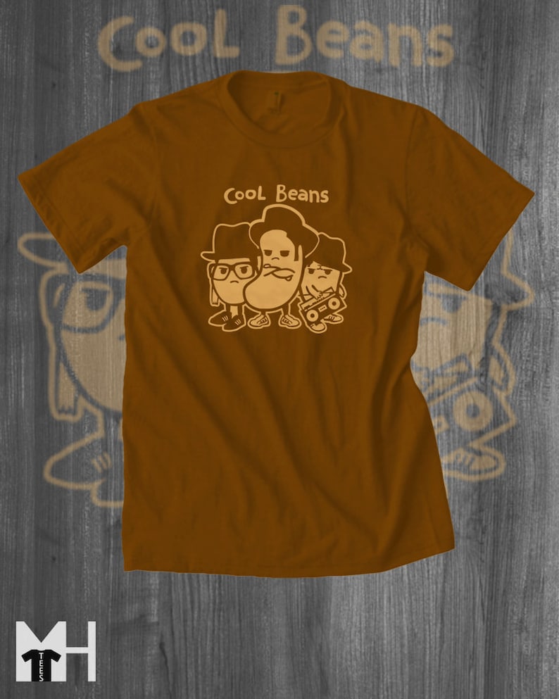 May include: A brown t-shirt with a graphic of three cartoon beans wearing hats and sunglasses. The text "Cool Beans" is printed above the beans.