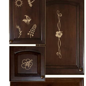 Könnte beinhalten: Vier Schranktüren und eine Schublade mit einer Holzoptik und goldfarbenen floralen und naturbezogenen Designs. Die Designs beinhalten einen Schmetterling, eine Libelle, eine Sonne, Blumen und Ranken.