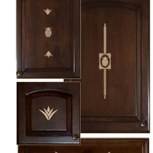 Op de afbeelding: Vier kastdeuren en een lade met een ananasmotief. De deuren en de lade zijn van donkerbruin hout met gouden ananasontwerpen.