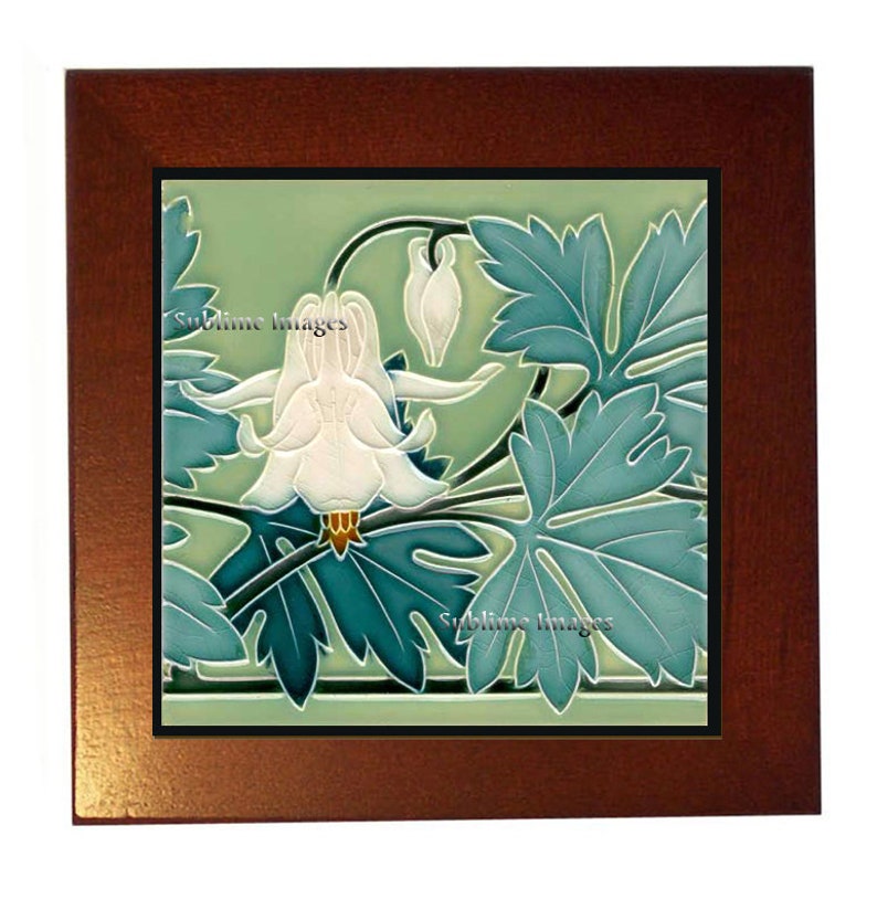 May include: A vintage ceramic tile with a green background featuring a white flower with blue-green leaves. The tile is framed in a dark wood frame.