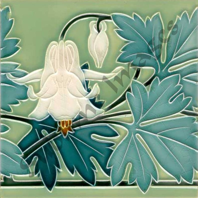 May include: A vintage ceramic tile with a green background and a white flower with blue leaves. The flower is in the center of the tile and the leaves are around it.