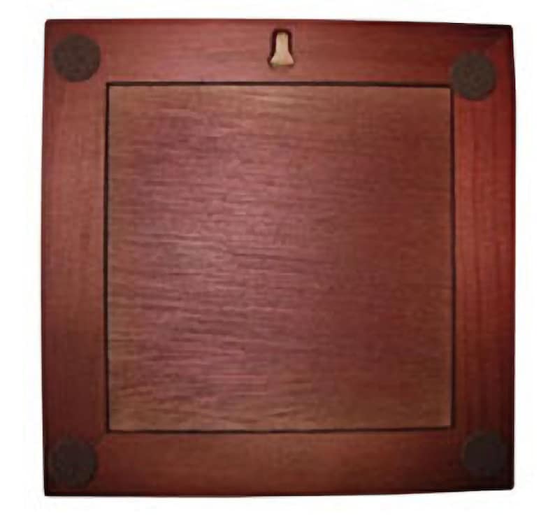 May include: A dark red wooden picture frame with a light brown mat and four black felt pads on the corners. The frame has a metal hanger on the back.
