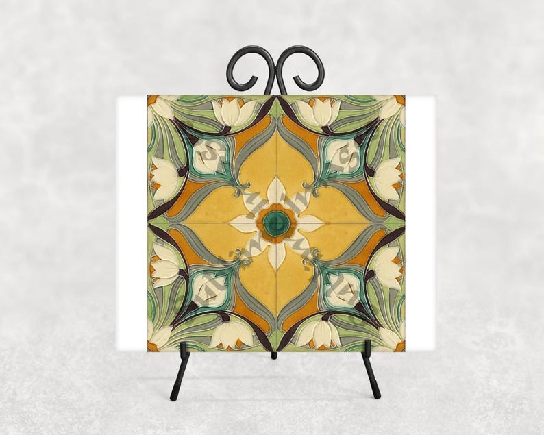 May include: A decorative tile with a floral design in yellow, green, and white, displayed on a black metal easel. The tile features a symmetrical pattern with stylized flowers and leaves, creating a vintage aesthetic.