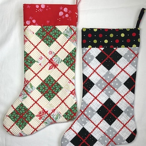 Peut inclure: Deux chaussettes de Noël avec un motif en losange. Une chaussette est rouge, verte et blanche avec un imprimé floral. L'autre chaussette est noire, blanche et grise avec des coutures rouges.