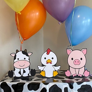 Farm animals cow, chicken and pig party table decorations.  Each centerpiece can stand on their own or add balloons and a balloon weight inside the kraft bag.  Each die cut measures approximately 9" tall.