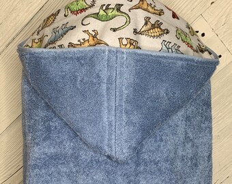 May include: A blue hooded towel with a white dinosaur print lining the hood.