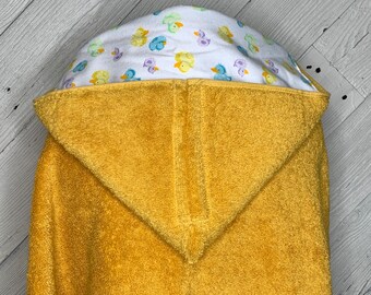 May include: A yellow hooded towel with a white lining featuring a pattern of colorful ducks. The towel is made of soft, absorbent terry cloth.