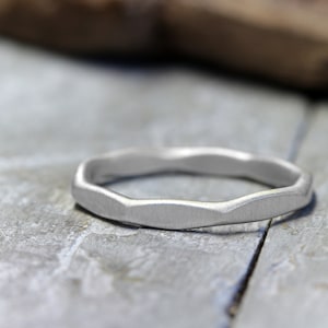 Könnte beinhalten: Ein silberner Ring mit einer strukturierten, wellenförmigen Band.