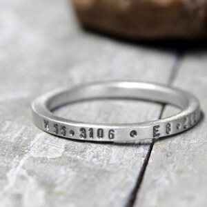 May include: A silver ring with the inscription "N 55.3106  E 8.201" engraved on the band.