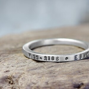 May include: A silver ring with the inscription "N 55. 3106  E 8. 230"