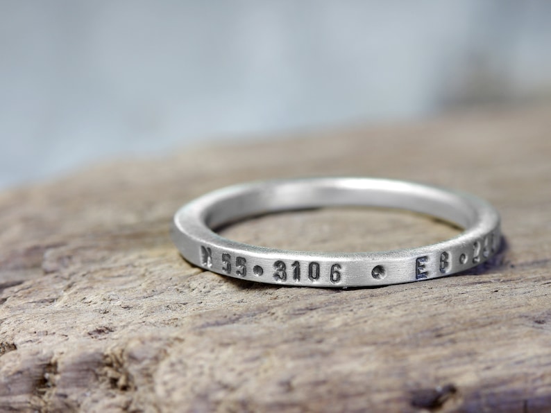May include: A silver ring with the inscription "N 55. 3106  E 8. 230"
