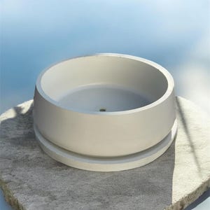 May include: A round, off-white planter with a matching saucer. The planter has a simple, modern design and sits on a textured, gray stone surface. The background is a soft blue gradient.