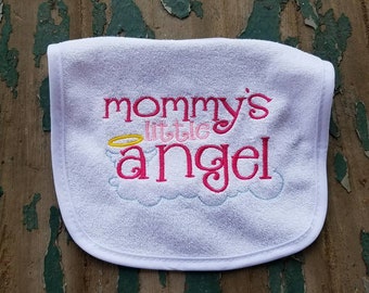 May include: White baby bib with pink and yellow embroidery that reads "mommy's little angel" with a halo above the word "angel".
