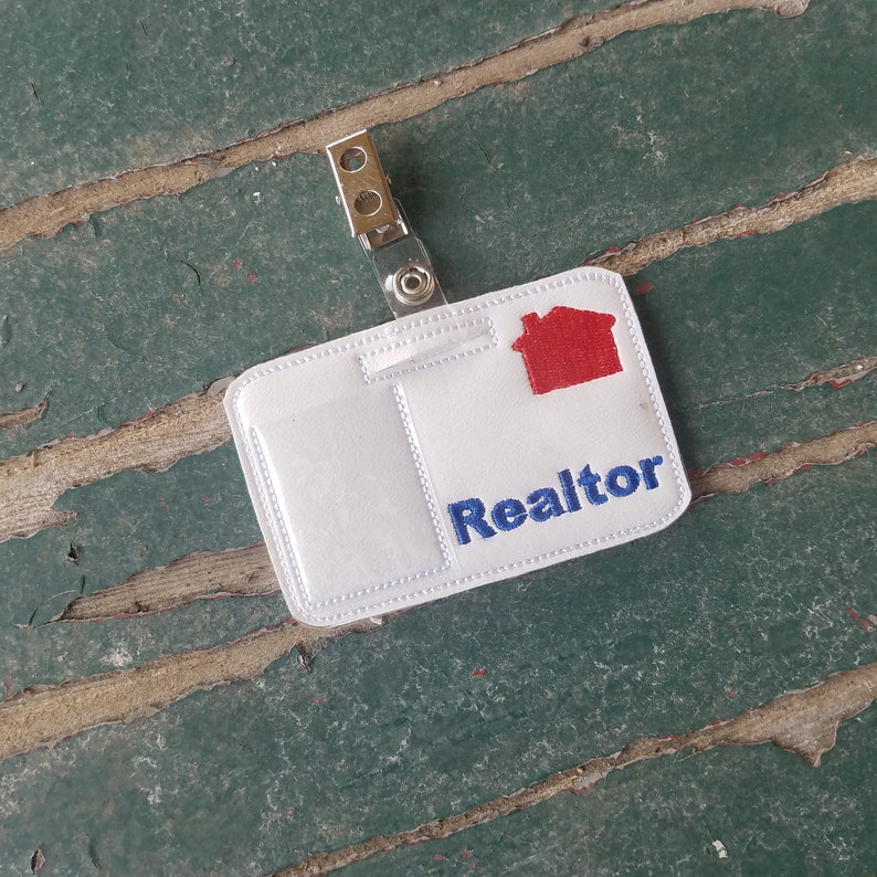 May include: White plastic realtor ID badge with a red house icon and blue text that says "Realtor".