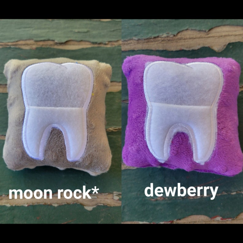 May include: Two plush tooth-shaped pillows, one in a light brown colour with the text "moon rock*" and the other in a purple colour with the text "dewberry".