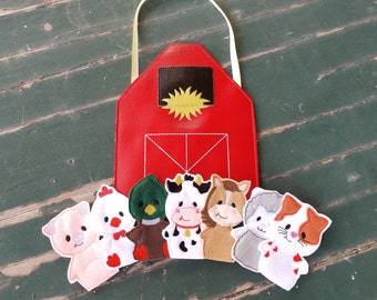 May include: A red felt barn with a white door and yellow sun design.  There are six felt finger puppets in front of the barn, including a cow, pig, chicken, horse, duck, and cat.