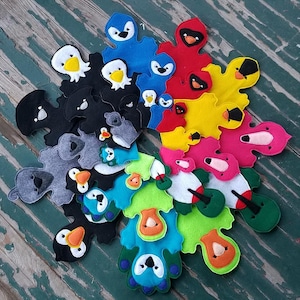 May include: A set of felt animal puppets in various colors, including black, gray, blue, green, yellow, pink, and red. Each puppet has a unique design and features a different animal face.