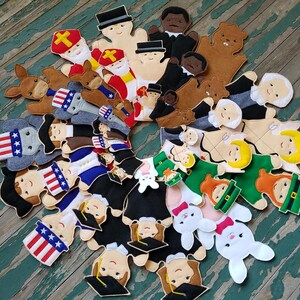 May include: A set of felt finger puppets featuring a variety of characters, including a donkey, a bear, a Santa Claus, a graduation cap, a bunny rabbit, and a variety of people. The puppets are all brightly colored and have a whimsical, handmade look.