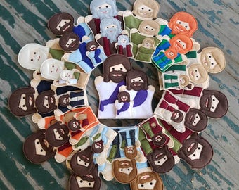 May include: A set of 20 felt finger puppets featuring various characters with different facial expressions and clothing. The puppets are arranged in a circle on a wooden surface.