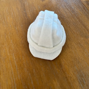 May include: A white felt hard hat, a miniature version of a construction worker's hat.