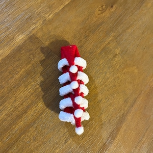 May include: A red and white felt Christmas tree ornament with a white pom-pom on top.