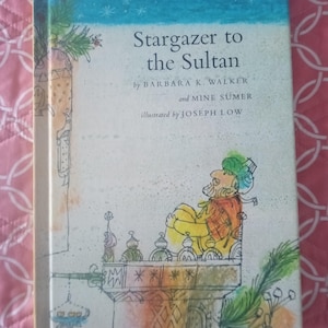 May include: A vintage book titled "Stargazer to the Sultan" with illustrations. The cover features a cartoon of a man in a turban. The book has a blue and white sky background and is set against a pink patterned background.