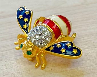 Broche vintage de abeja patriótica en tonos dorados de Joan Rivers, con diseño de abeja en rojo, blanco y azul, broche de estrellas y rayas de Joan Rivers.