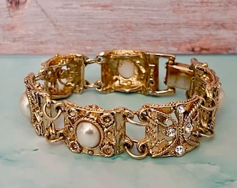 May include: A gold-tone bracelet with a chain link design. The bracelet features faux pearls and rhinestones.