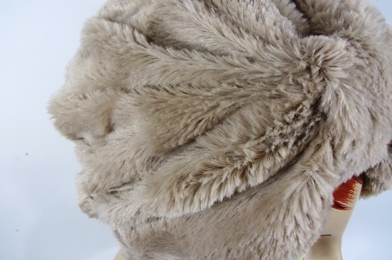 May include: A close-up of a light brown faux fur fabric. The fabric has a soft, fluffy texture and is ideal for crafting projects.