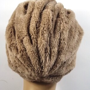 May include: A brown faux fur hat with a gathered, pleated design. The hat is soft and fluffy.
