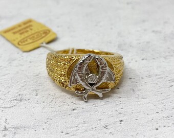 May include: Gold ring with a textured band and a silver design of two fish intertwined. The fish have a small diamond in the centre.
