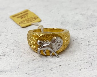 May include: A gold ring with a textured band and a silver lion head design.