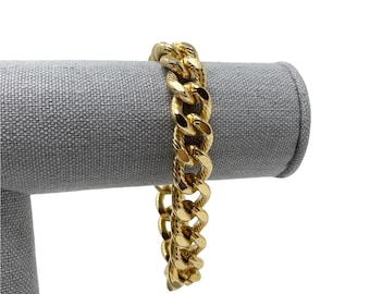 May include: A gold-toned chain bracelet with a curb link design. The bracelet is displayed on a gray fabric stand.
