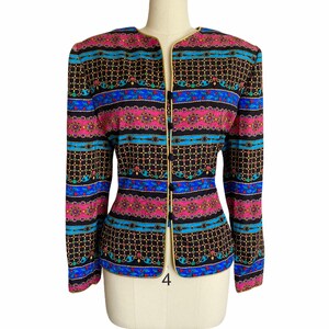 May include: A black blazer with a colorful geometric pattern featuring pink, blue, and gold accents. The blazer has a gold trim and a single button closure.