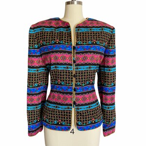May include: A black blazer with a colorful patterned design featuring gold chains, pink, blue, and green accents. The blazer has a gold trim and a single button closure.