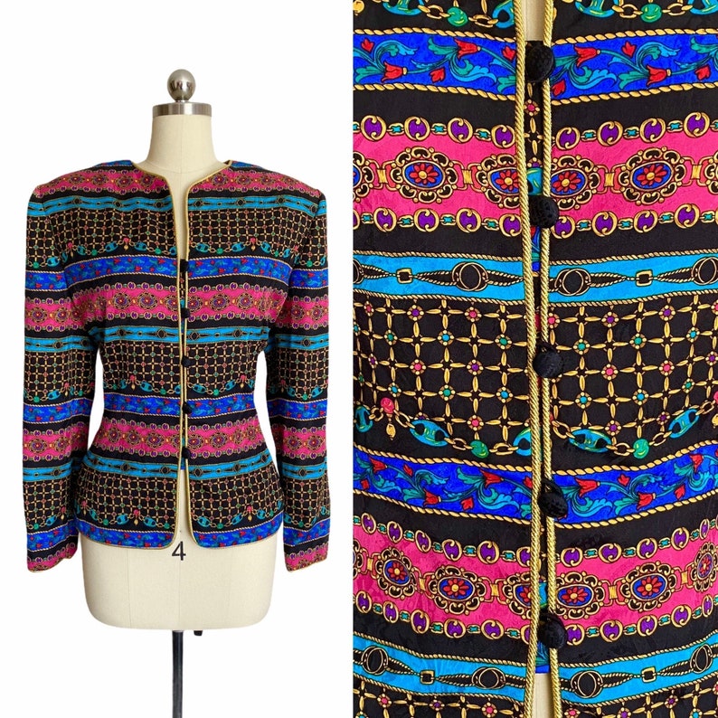 May include: A black blazer with a colorful patterned design featuring chains, flowers, and geometric shapes. The blazer has a gold trim and buttons.