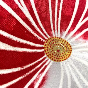 May include: Close-up of a floral design with red petals and white stripes radiating from a yellow and red center. The fabric has a textured appearance, with a detailed pattern.