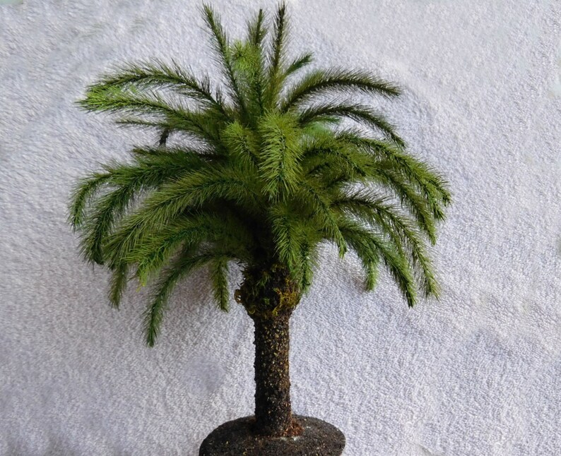 May include: A small artificial palm tree with green fronds and a brown trunk. The tree is potted in a dark brown pot.