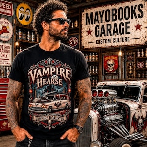Puede incluir: Una camiseta negra con un estampado gráfico de un coche fúnebre blanco con un motor grande, murciélagos y arquitectura gótica. El texto dice VAMPIRE HEARSE y VAMPIRE ROADSTER. El diseño incluye linternas rojas y una calavera.