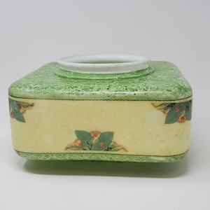 May include: Square ceramic vase with a green and yellow floral design. The vase has a white rim and a textured surface.