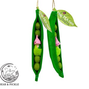 May include: Two felt pea pods, each with green peas and a gnome. The gnomes have pink hats and green tunics. Each pod has a leaf-shaped tag that reads "Hap PEA ness". The logo for Bear & Pickle is in the lower left.