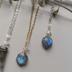 May include: Three necklaces with different chain styles and gemstone pendants. The pendants are all hexagonal and feature a blue labradorite stone. The chains are silver, gold, and silver.