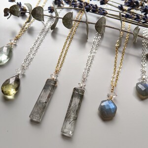 May include: Six necklaces with different crystal pendants. The pendants include a teardrop-shaped green crystal, a teardrop-shaped yellow crystal, a long rectangular clear crystal with black inclusions, a long rectangular clear crystal with black inclusions, a hexagonal blue crystal, and a hexagonal blue crystal.