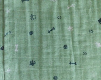 May include: A green fabric with a repeating pattern of paw prints, bones, and tennis balls.
