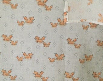 May include: White fabric with a repeating pattern of orange foxes. The foxes are running and have a small fox following behind them.