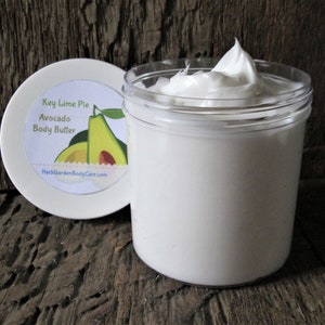 May include: A white jar of Key Lime Pie Avocado Body Butter with a white lid featuring a green avocado illustration and the text "Key Lime Pie Avocado Body Butter" and "HerbGardenBodyCare.com".