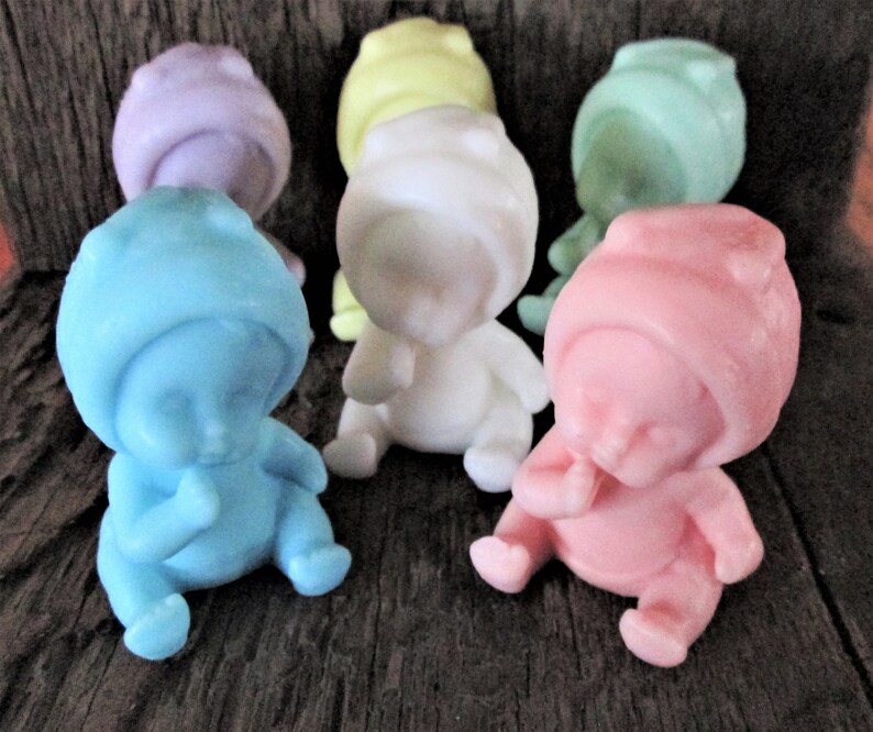 May include: Six small baby-shaped soaps in various pastel colors, including blue, pink, white, yellow, and purple. Each soap is shaped like a baby with a hooded hat and a finger in its mouth.