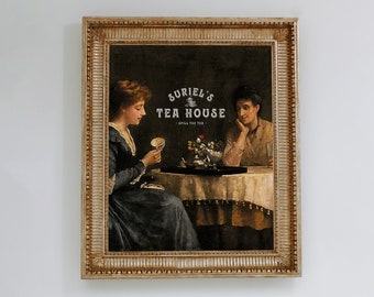May include: A framed vintage print depicting two women at a table, with the text "Suriel's Tea House" at the top. The women are in period dress, and a small tea set is on the table. The frame is ornate and gold-toned.