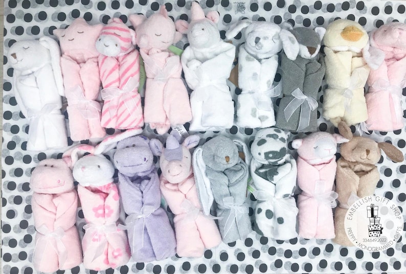 May include: A collection of 15 plush baby blankets, each featuring a different animal design. The blankets are rolled up and tied with a ribbon. The animals include a bunny, a unicorn, a dog, a cat, a hippo, a giraffe, a zebra, a cow, a pig, a duck, and a bear. The blankets are all in pastel colors, such as pink, blue, yellow, and green. The blankets are perfect for babies and toddlers.
